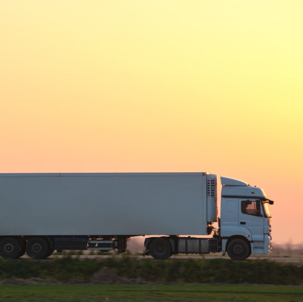 Semi-truck with cargo trailer driving on highway hauling goods in evening. Delivery transportation and logistics concept.